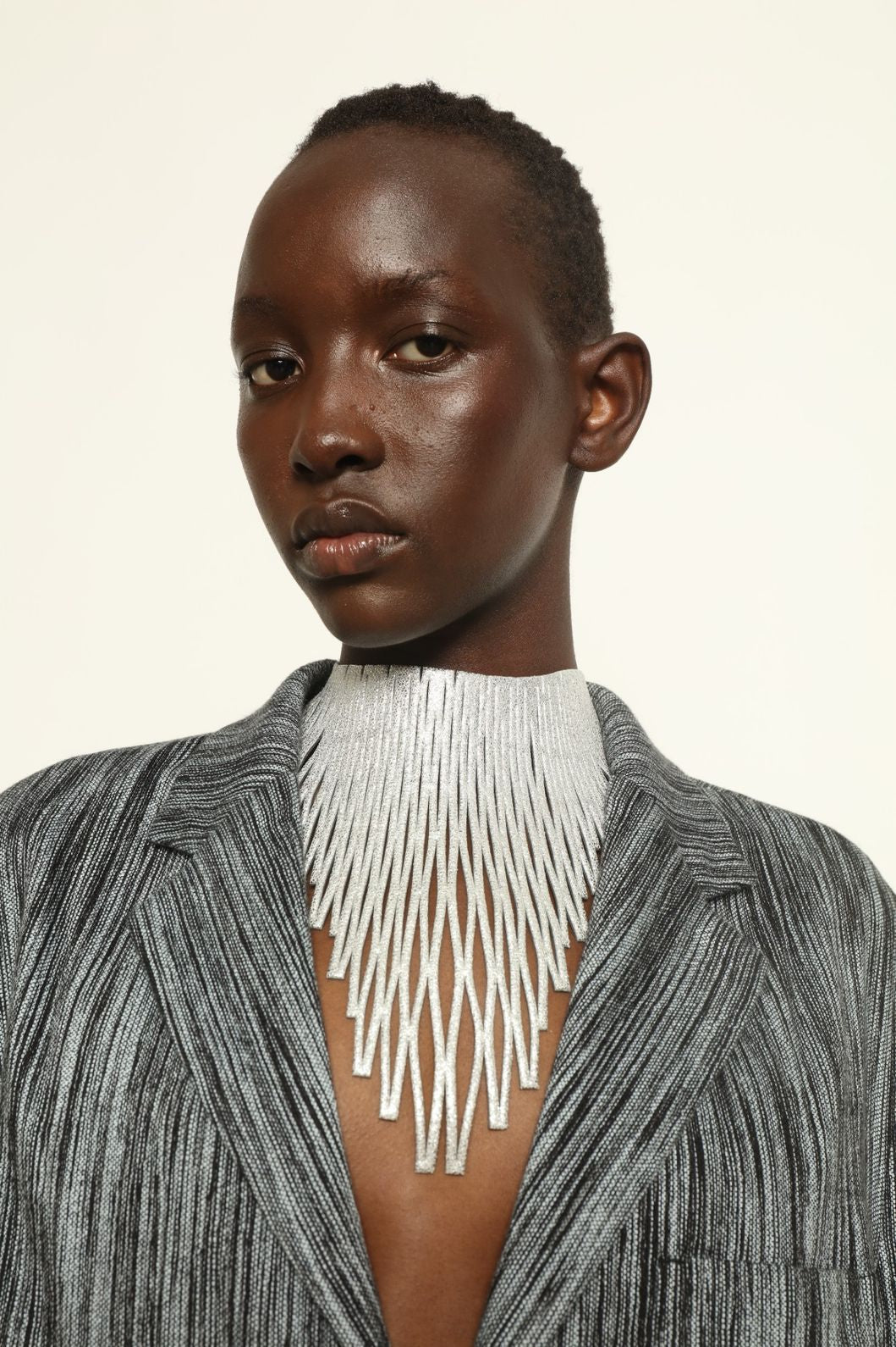 Model is wearing Luminous Silver Leather Necklace by SO-LE STUDIO, handcrafted from upcycled Italian leather with slender diamond-shaped elements forming a fluid, radiant cascade around the neckline, part of the curated selection at House of Woven Stories, combining lightweight elegance with sculptural design.