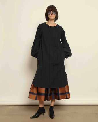 Model is wearing the Lulu Dress by House of Woven Stories in navy blue with voluminous sleeves, A-line silhouette.