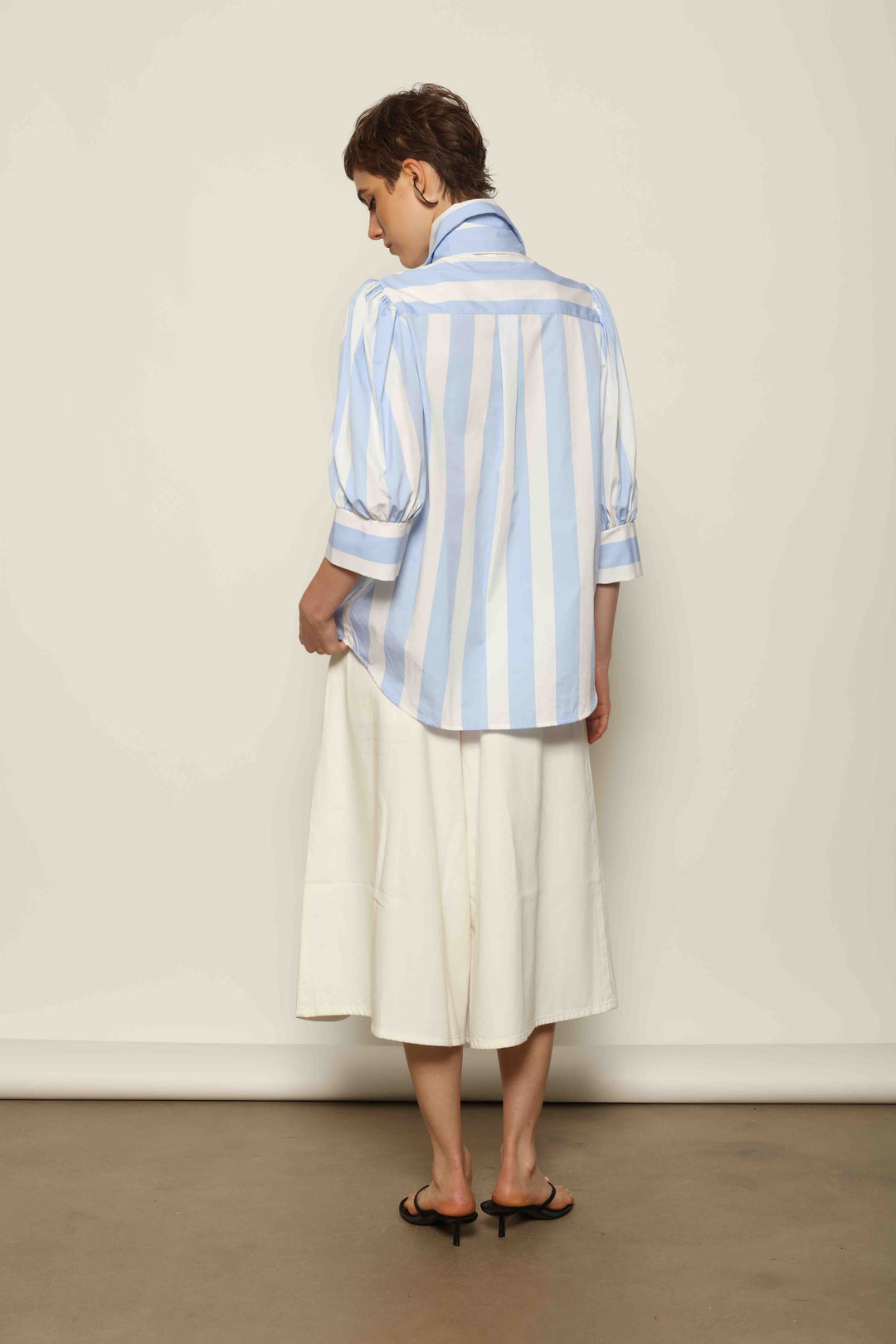 Back view of La Jupe Culotte in Blanc Cassè, highlighting the refined welt pockets and embroidered peacock detail.