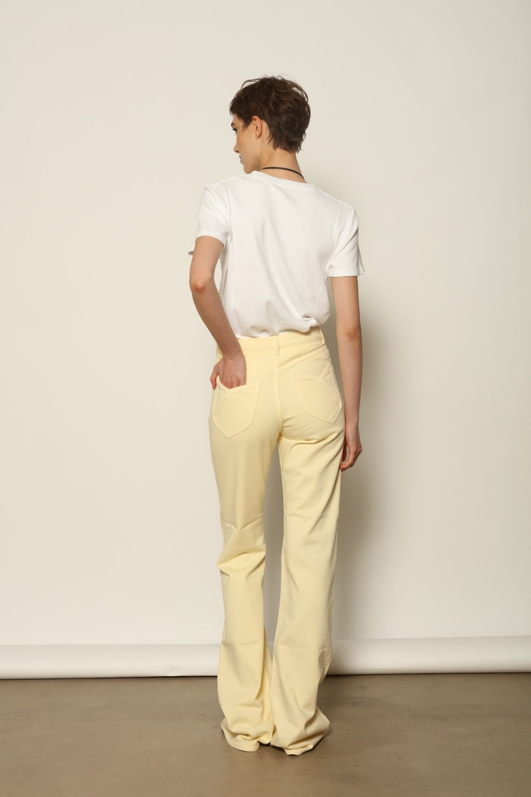 Back view of Le Pantalon Tulipe in Banana by HAPPY HAUS, highlighting the five pocket construction and embroidered peacock detail.