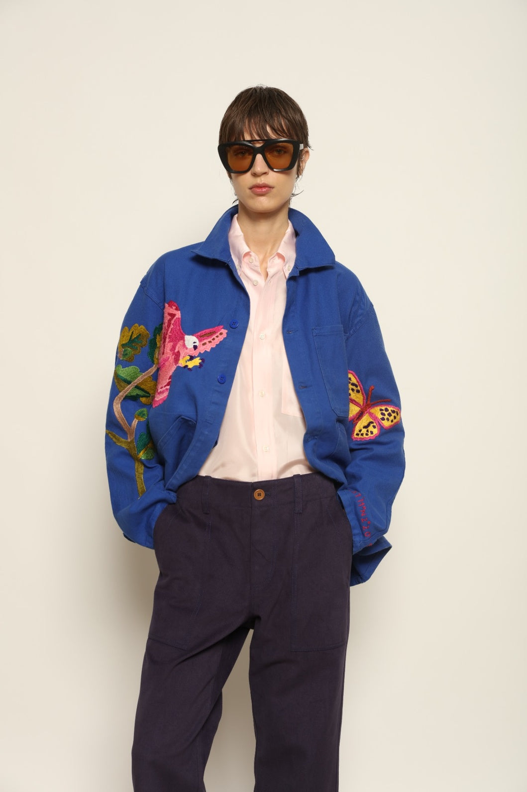 Person wearing a blue jacket with colorful designs on a plain background