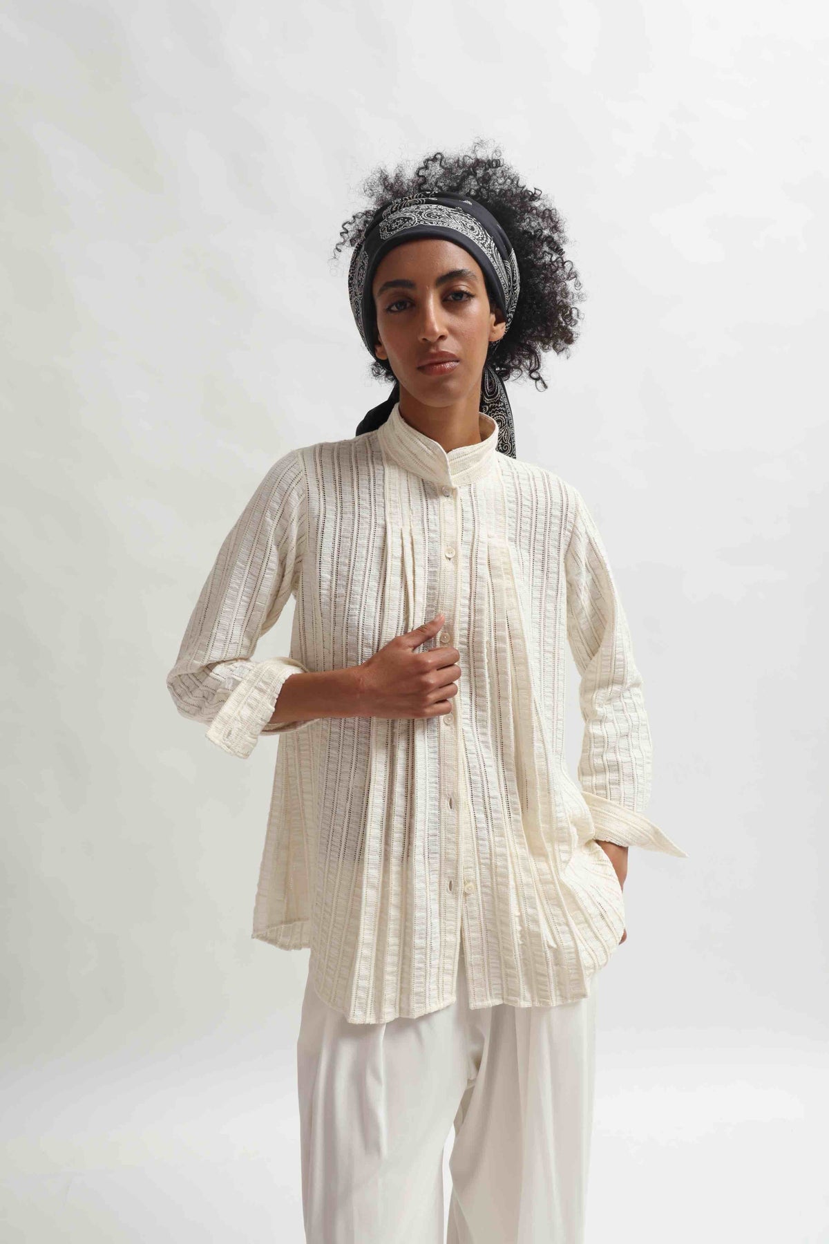 Leno Pleated Shirt by Paiwand made from upcycled cotton with breathable leno weave, featuring elegant pleats and handcrafted in India. Sustainable fashion curated by House of Nomad Stories.