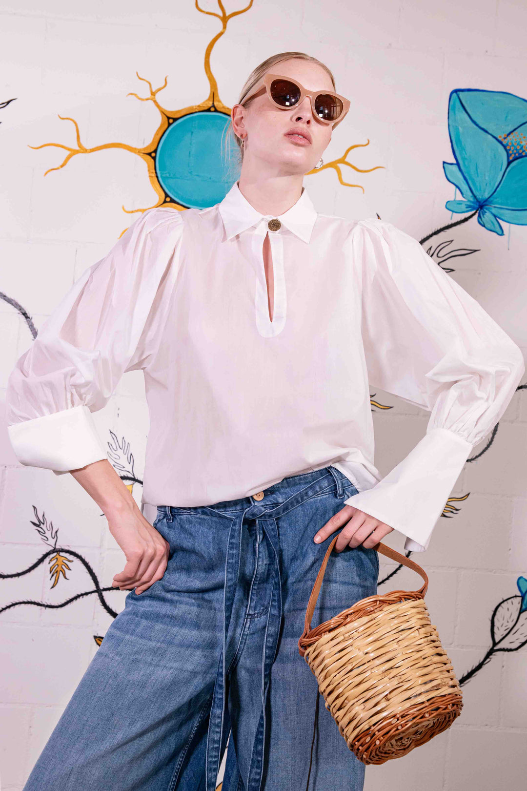 Model is wearing a white V-neck cotton blouse with relaxed fit, wide cuffs, and vintage button detail by House of Woven Stories.