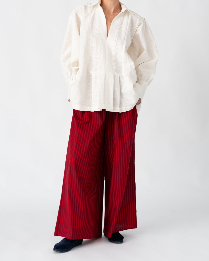Model is wearing the Ancestral White Linen Shirt by Les Vacances d’Irina, a unisex handmade linen shirt with relaxed cut, open V-neckline, and natural shell buttons, crafted in Bucharest and available at House of Nomad Stories.