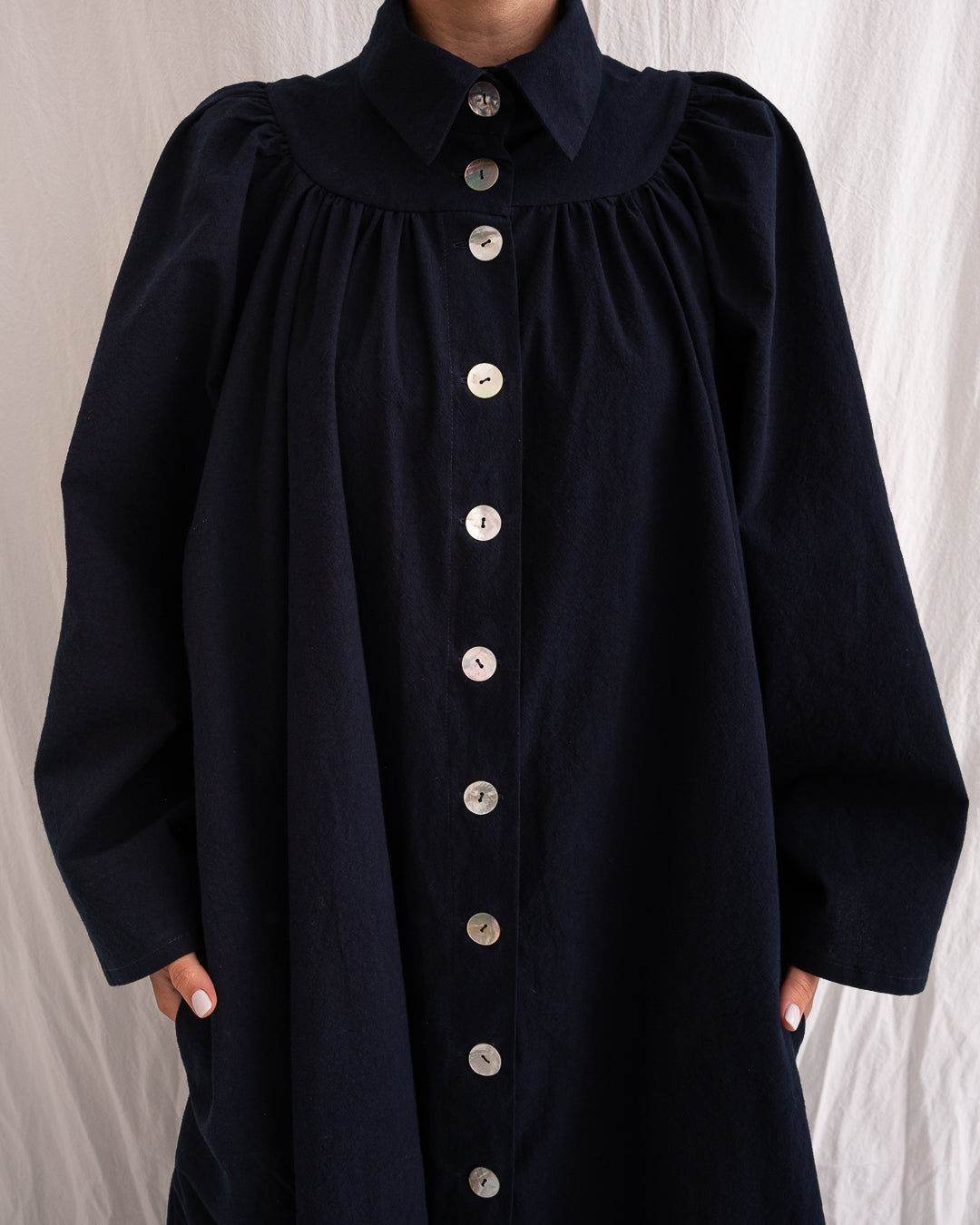 A Bigger Splash Cotton Dress by Les Vacances d’Irina, full-length long-sleeved maxi dress in ivory cotton with shell buttons, high collar, and hidden side pockets, handmade in Romania.