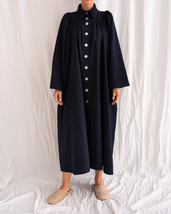A Bigger Splash Cotton Dress by Les Vacances d’Irina, full-length long-sleeved maxi dress in ivory cotton with shell buttons, high collar, and hidden side pockets, handmade in Romania.