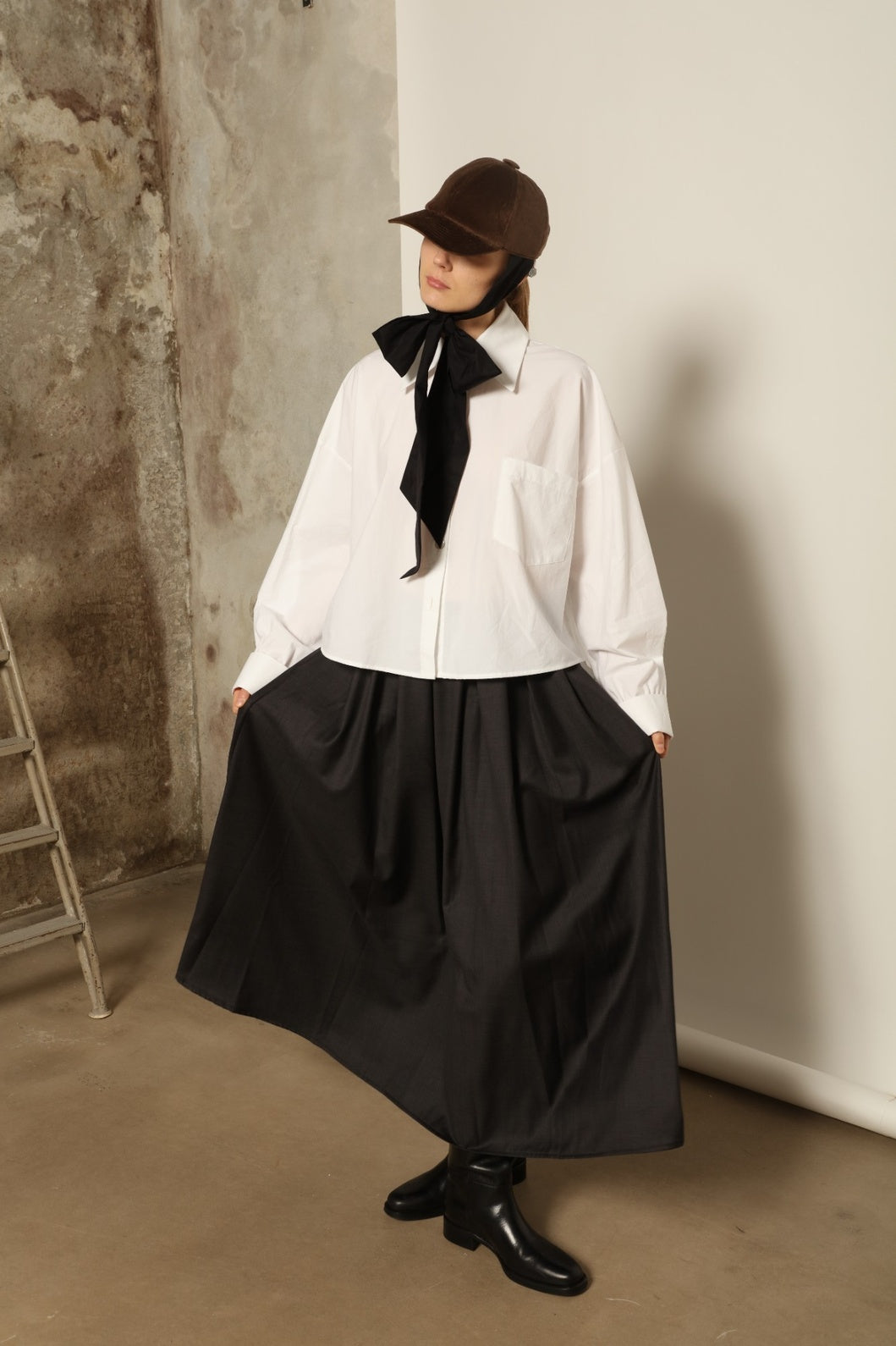 Model is wearing the Bettina White Organic Cotton Blouse by House of Nomad Stories, featuring a straight silhouette, classic collar, button-front closure, and oversized chest pocket.