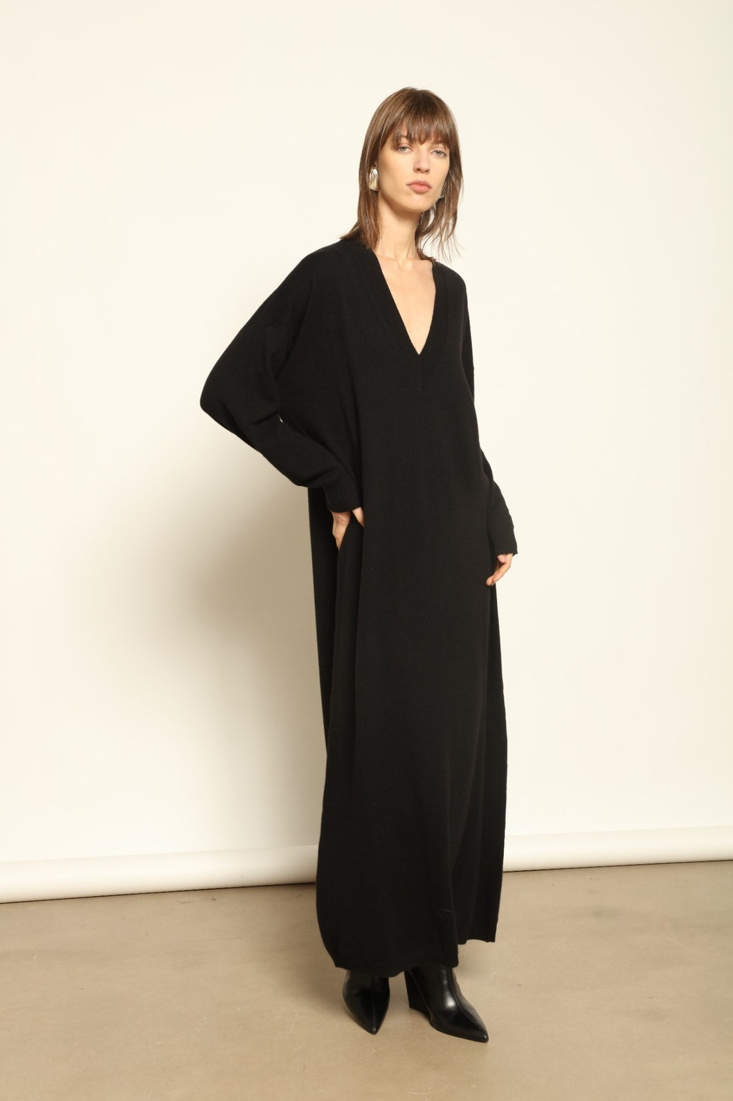 Model wearing the Black Katharina V-Neck Cashmere Maxi Dress by House of Nomad Stories, crafted in Italy from 100% pure Inner Mongolia cashmere, featuring a flowing silhouette, soft drape, and timeless sustainable black knitwear design