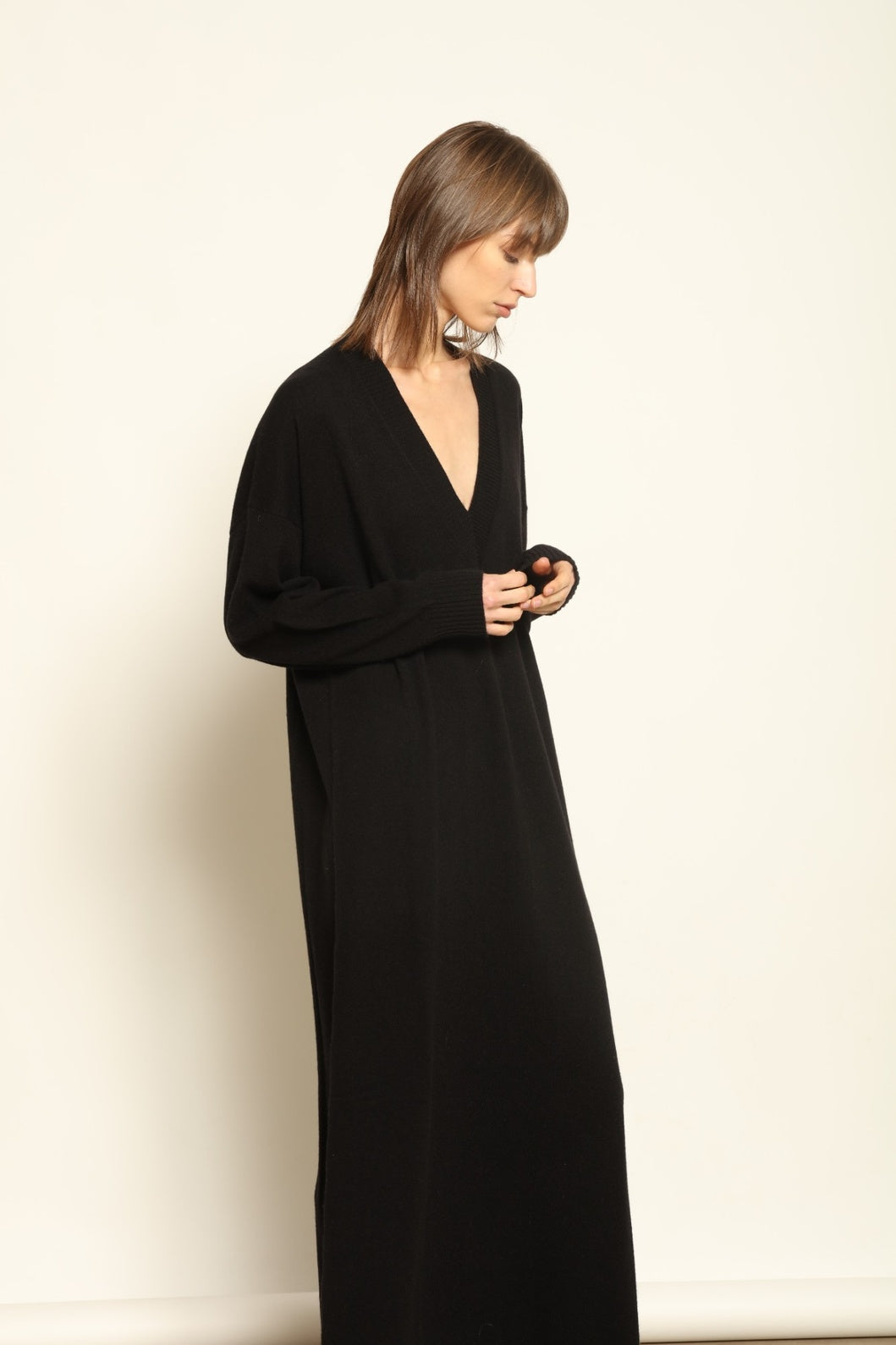 Model wearing the Black Katharina V-Neck Cashmere Maxi Dress by House of Nomad Stories, crafted in Italy from 100% pure Inner Mongolia cashmere, featuring a flowing silhouette, soft drape, and timeless sustainable black knitwear design