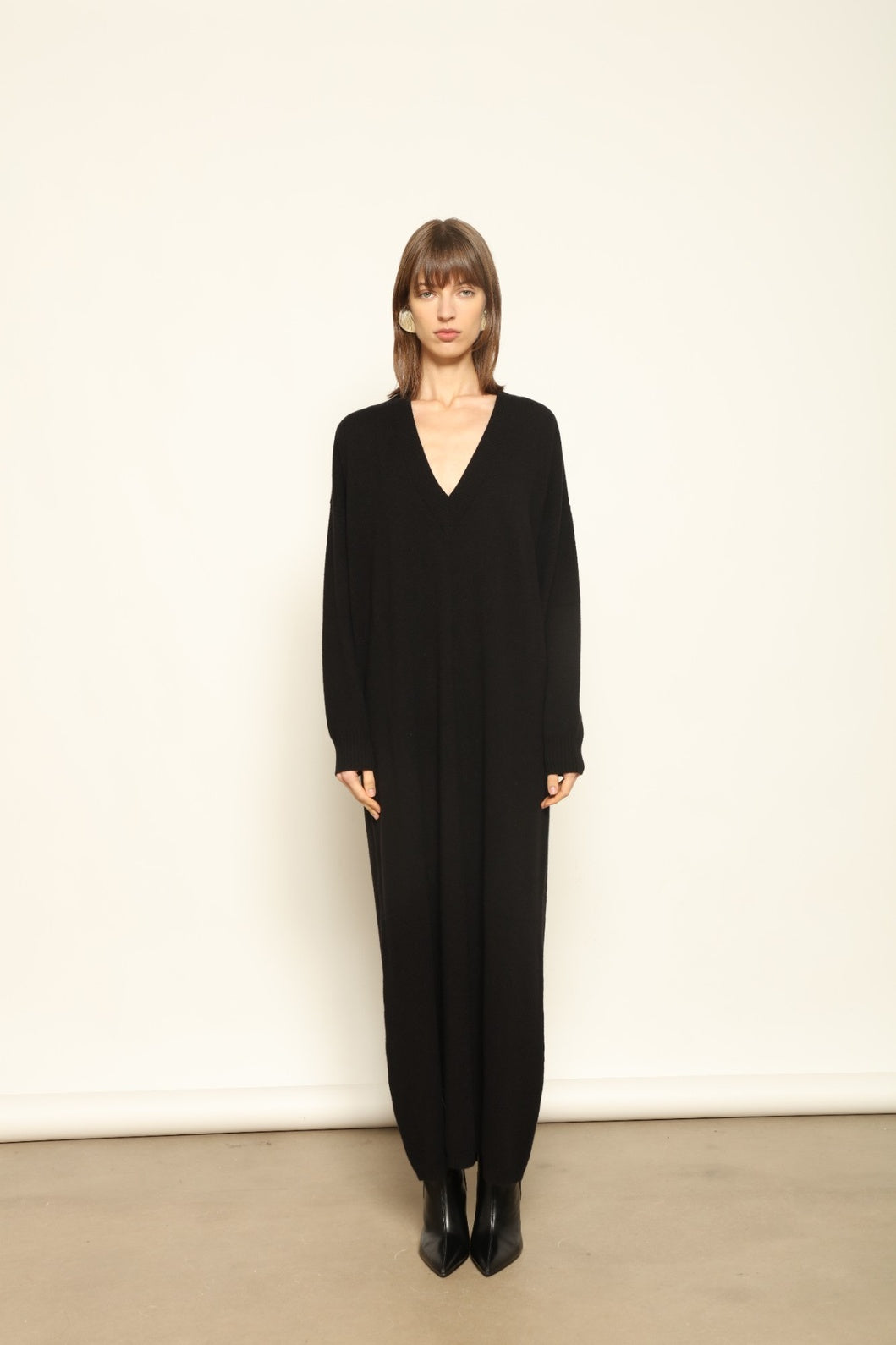 Model wearing the Black Katharina V-Neck Cashmere Maxi Dress by House of Nomad Stories, crafted in Italy from 100% pure Inner Mongolia cashmere, featuring a flowing silhouette, soft drape, and timeless sustainable black knitwear design