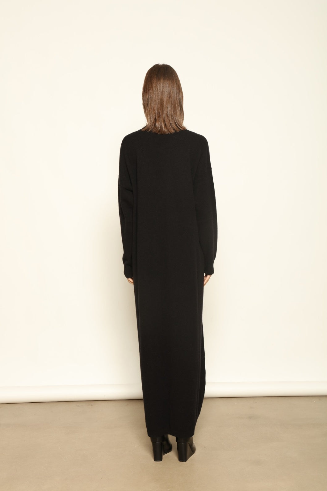Model wearing the Black Katharina V-Neck Cashmere Maxi Dress by House of Nomad Stories, crafted in Italy from 100% pure Inner Mongolia cashmere, featuring a flowing silhouette, soft drape, and timeless sustainable black knitwear design