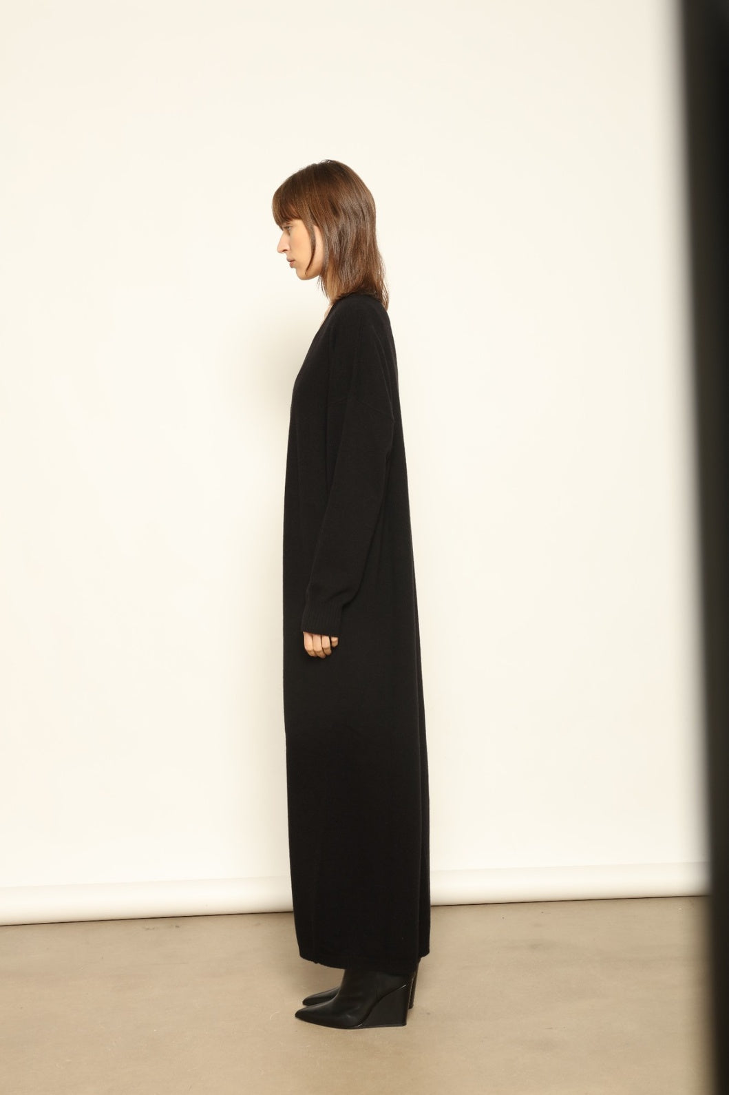 Model wearing the Black Katharina V-Neck Cashmere Maxi Dress by House of Nomad Stories, crafted in Italy from 100% pure Inner Mongolia cashmere, featuring a flowing silhouette, soft drape, and timeless sustainable black knitwear design