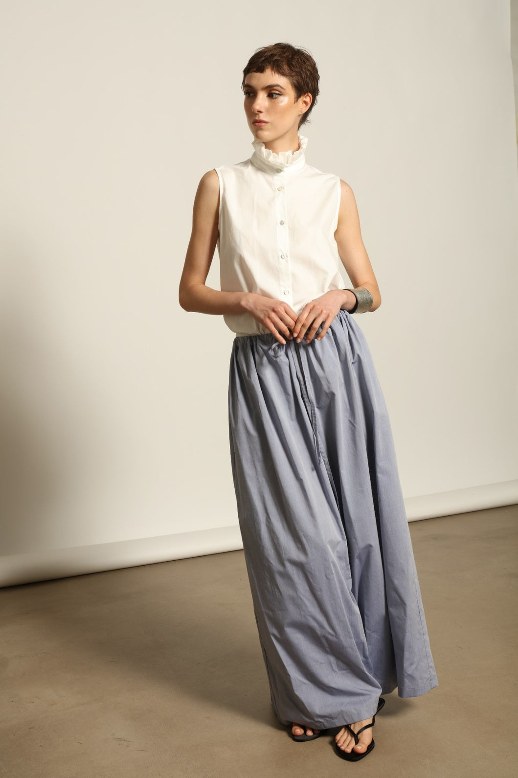 Model is wearing the Brigitta dusty blue cotton mousseline trousers from the House of Nomad Stories selection, lightweight and breathable women’s summer pants made in Italy in Piedmont, crafted from 100% natural cotton with a relaxed tailored silhouette designed for effortless movement.