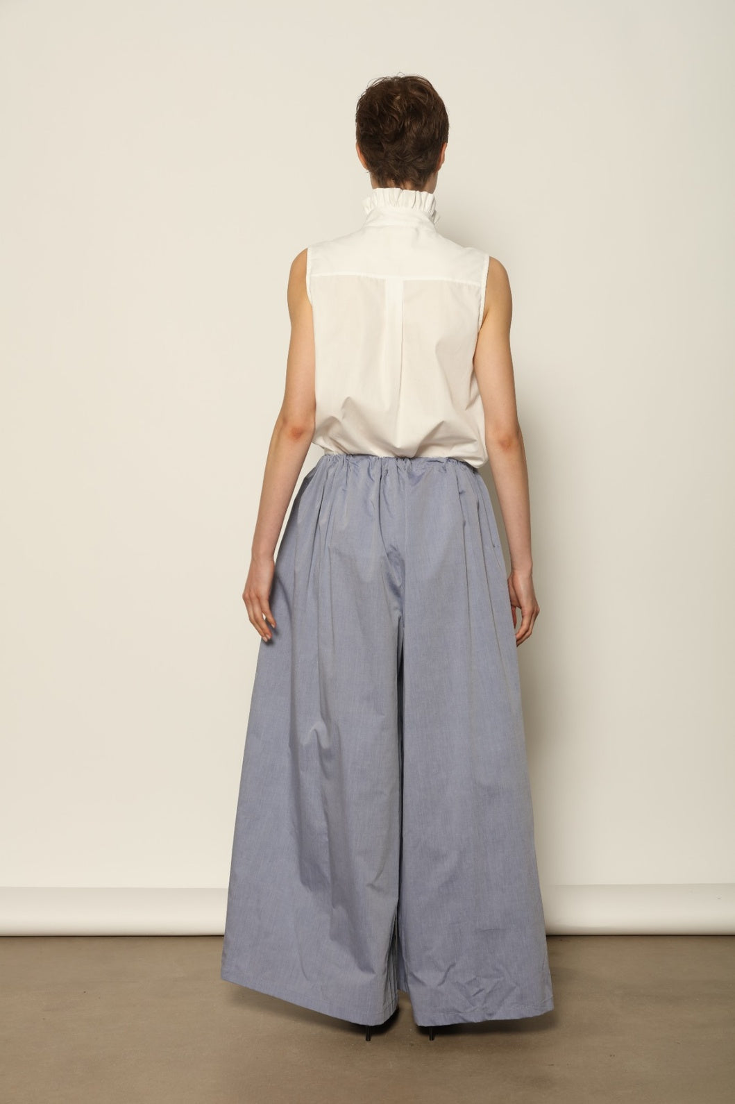 Model is wearing the Brigitta dusty blue cotton mousseline trousers from the House of Nomad Stories selection, lightweight and breathable women’s summer pants made in Italy in Piedmont, crafted from 100% natural cotton with a relaxed tailored silhouette designed for effortless movement.
