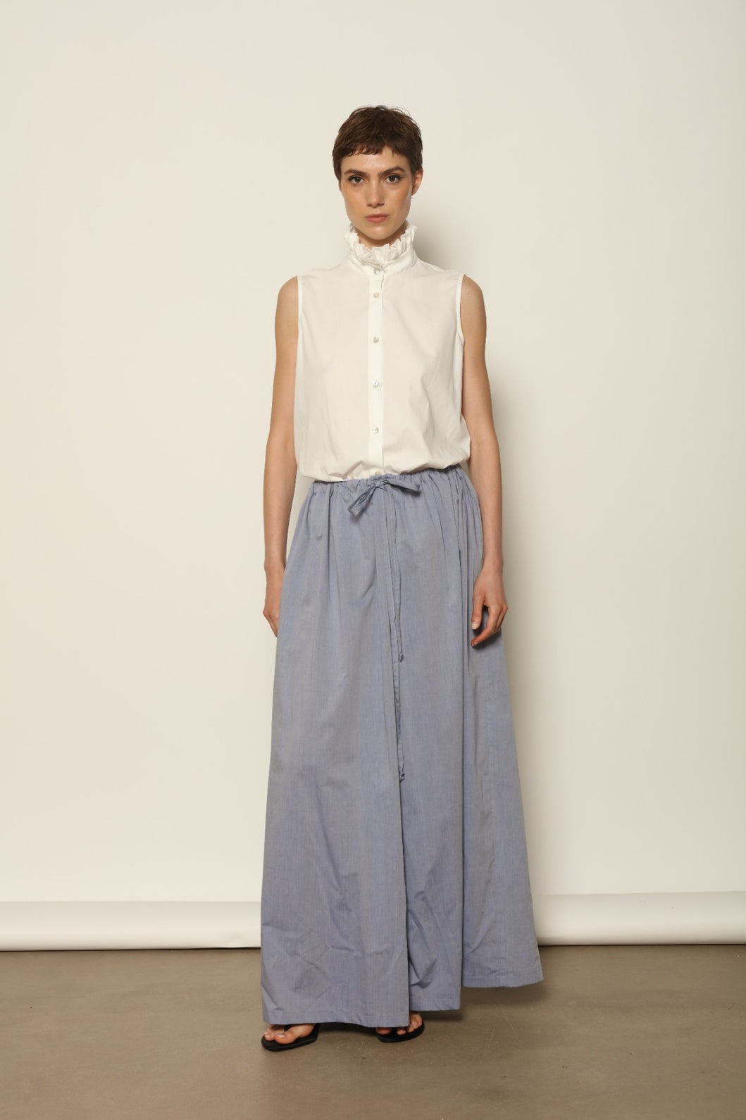 Model is wearing the Brigitta dusty blue cotton mousseline trousers from the House of Nomad Stories selection, lightweight and breathable women’s summer pants made in Italy in Piedmont, crafted from 100% natural cotton with a relaxed tailored silhouette designed for effortless movement.