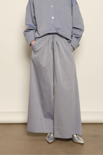 Model is wearing the Brigitta dusty blue cotton mousseline trousers from the House of Nomad Stories selection, lightweight and breathable women’s summer pants made in Italy in Piedmont, crafted from 100% natural cotton with a relaxed tailored silhouette designed for effortless movement.