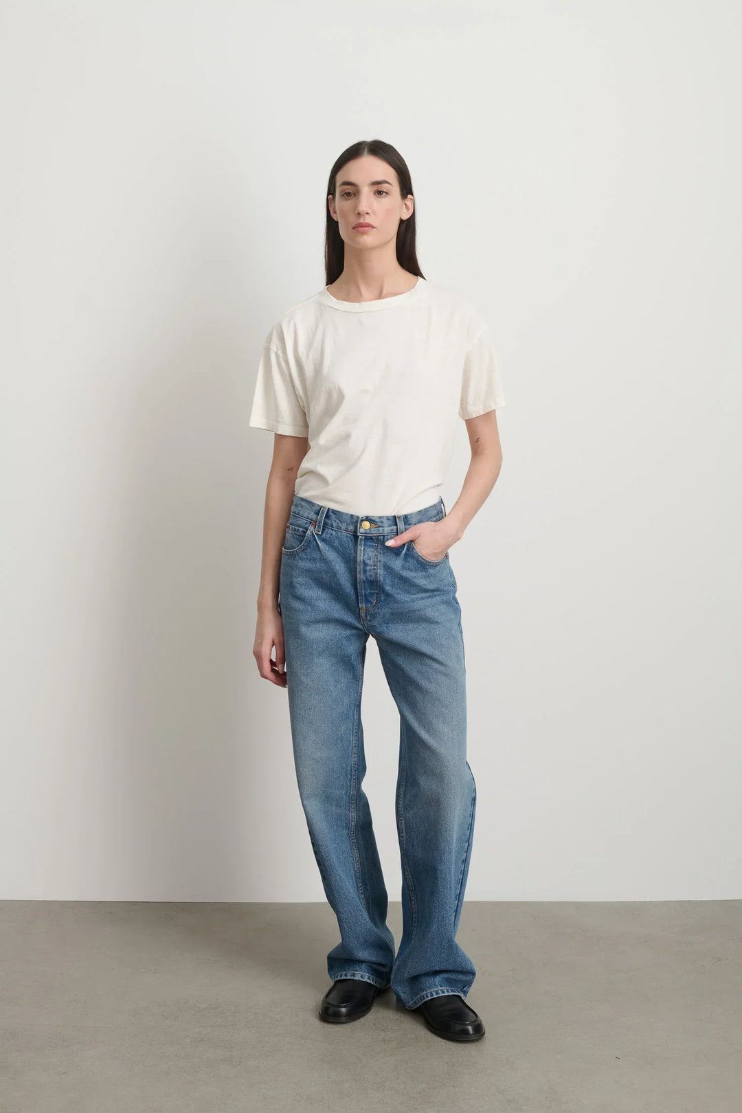 Model is wearing Bec Cotton Jean Halle Wash by B Sides in pale blue stone washed cotton denim with mid-rise straight leg fit, zip fly and brass button closure, available at House of Nomad Stories