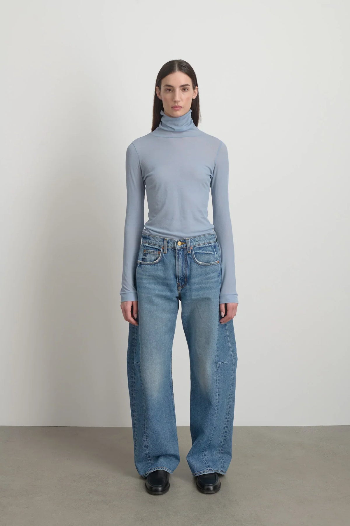 Model is wearing Relaxed Cuffed Lasso Jean Jane Wash by B Sides in pale blue stone washed cotton-rich denim with high waist, pieced outseam, kinked leg and raw hem, available at House of Nomad Stories