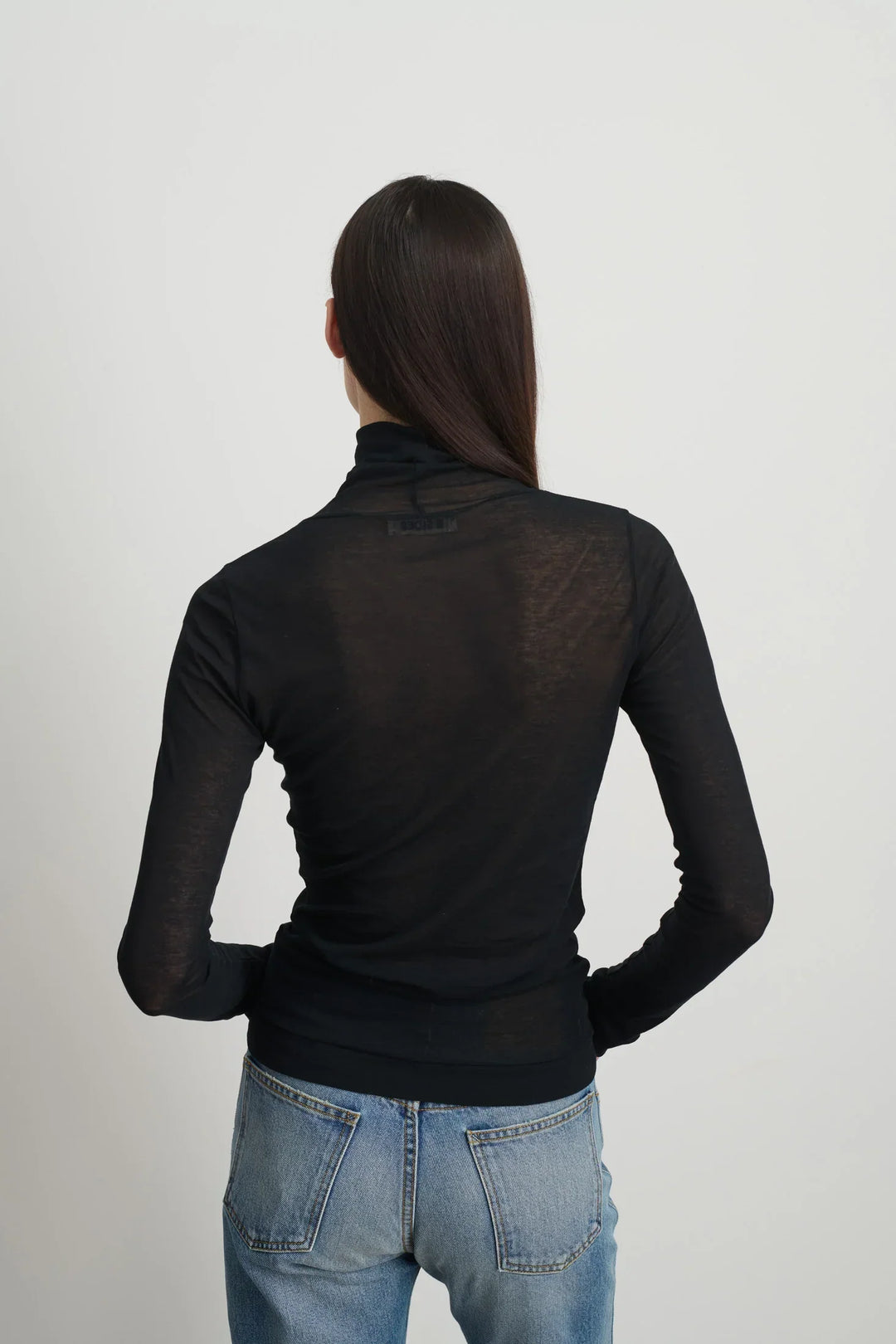 Model is wearing Jana Cotton Turtleneck in Black by B Sides in Japanese-milled black rib crepe with long sleeves, second-skin fit and raw finishing details, available at House of Nomad Stories