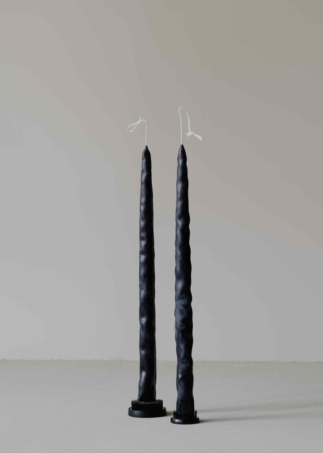 Carambola Low in Black candle holder by Oberflacht, part of the House of Nomad Stories selection, handmade from beeswax and paraffin with matching twig candle and natural variations in colour and texture.