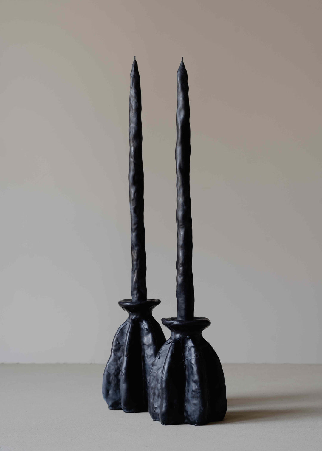 Carambola Low in Black candle holder by Oberflacht, part of the House of Nomad Stories selection, handmade from beeswax and paraffin with matching twig candle and natural variations in colour and texture.