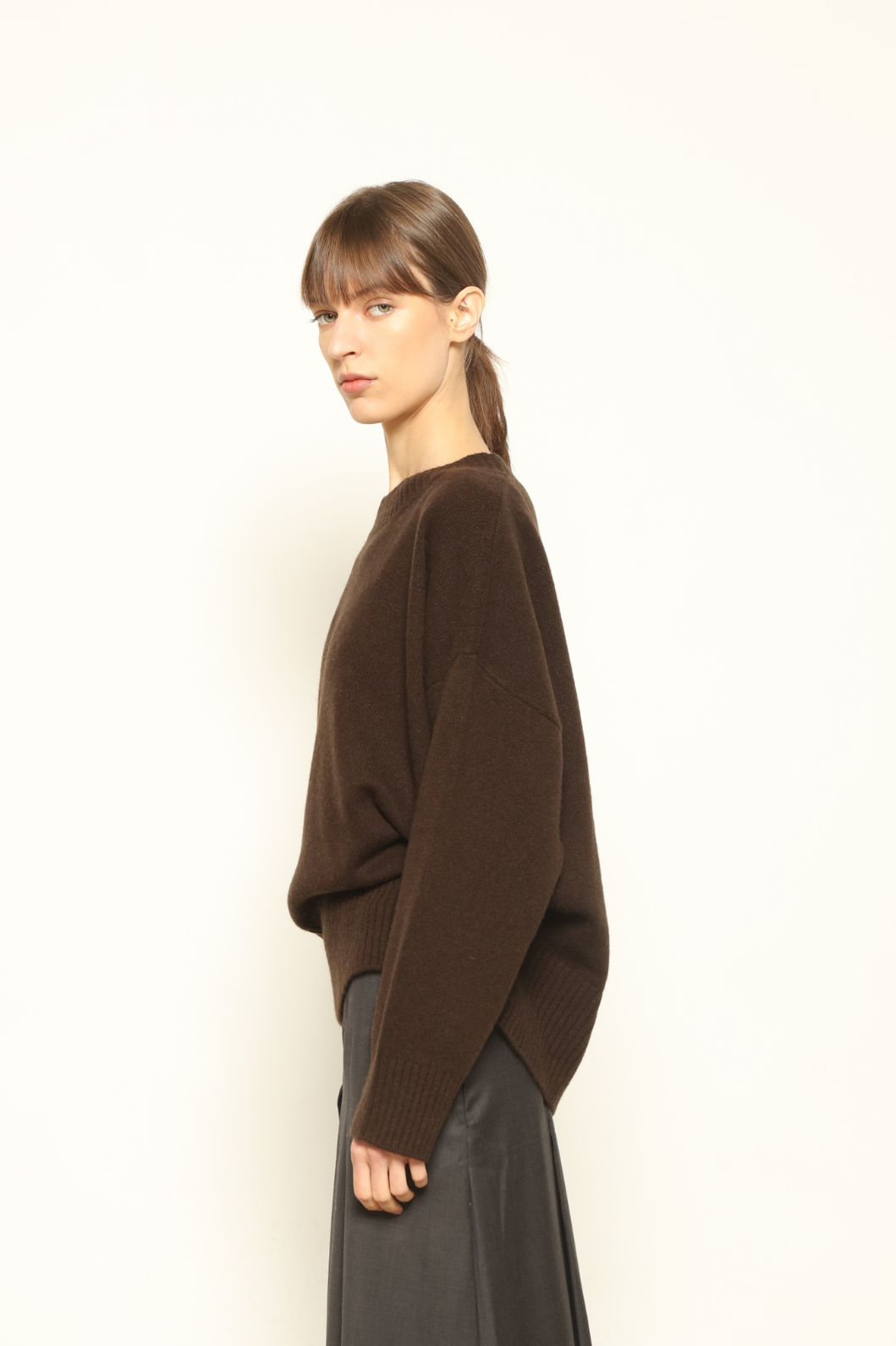 Model is wearing the chocolate Noemi Round Neck Pullover by House of Nomad Stories, made from 100% pure Inner Mongolia cashmere, featuring ultra-soft, breathable, durable knitwear, relaxed fit, and timeless luxury craftsmanship