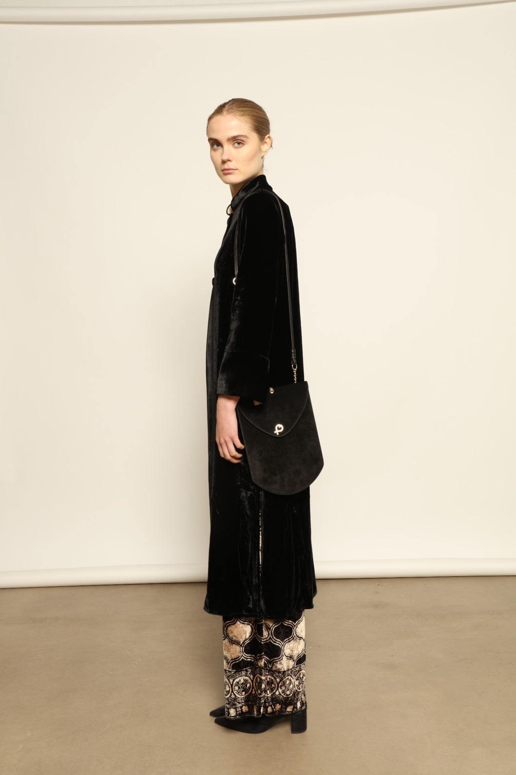 Model is wearing the Cleo Black Long Jacket VR.40 by Obidi, crafted from luxurious velvet with a structured silhouette and refined texture, combining artisanal craftsmanship with contemporary style.