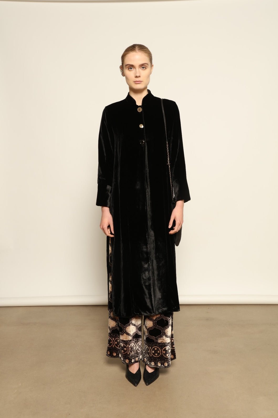 Model is wearing the Cleo Black Long Jacket VR.40 by Obidi, crafted from luxurious velvet with a structured silhouette and refined texture, combining artisanal craftsmanship with contemporary style.
