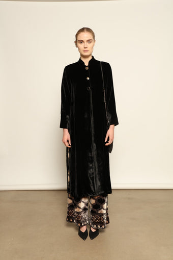 Model is wearing the Cleo Black Long Jacket VR.40 by Obidi, crafted from luxurious velvet with a structured silhouette and refined texture, combining artisanal craftsmanship with contemporary style.