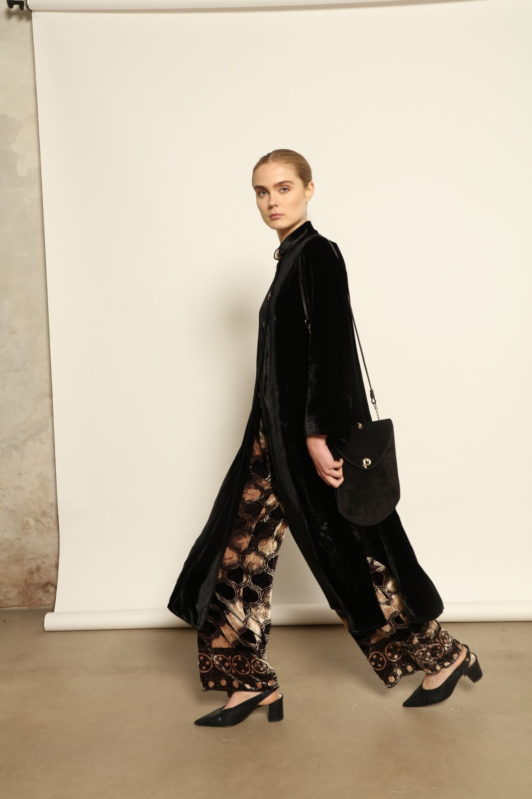 Model is wearing the Cleo Black Long Jacket VR.40 by Obidi, crafted from luxurious velvet with a structured silhouette and refined texture, combining artisanal craftsmanship with contemporary style.