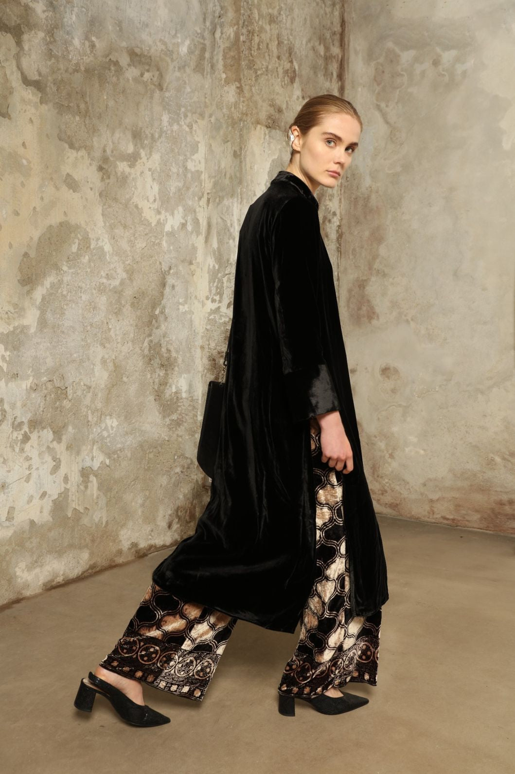 Model is wearing the Cleo Black Long Jacket VR.40 by Obidi, crafted from luxurious velvet with a structured silhouette and refined texture, combining artisanal craftsmanship with contemporary style.