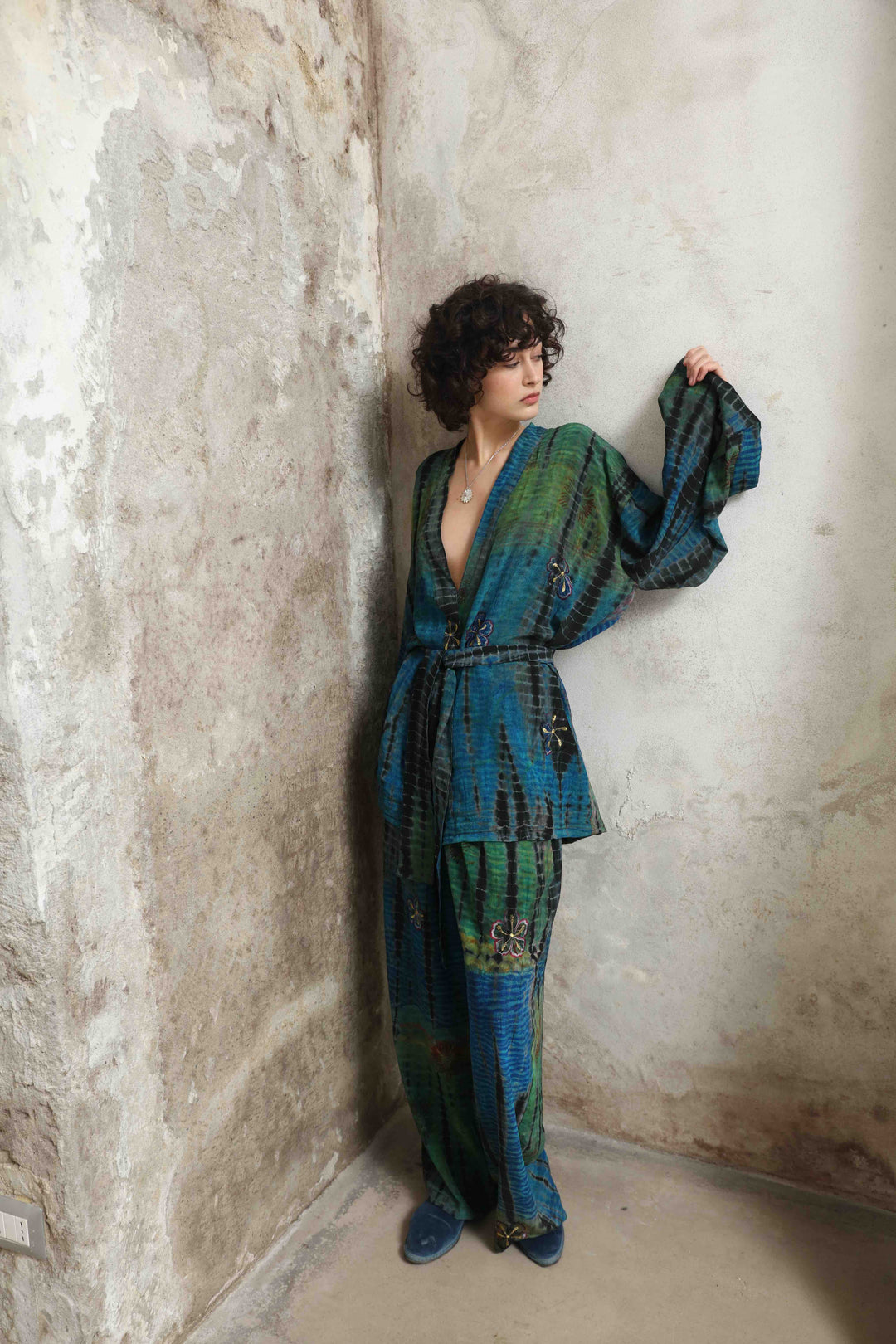 Model is wearing the Deep Teal Gorana Kimono Suit by House of Nomad Stories, featuring a relaxed silk kimono with matching belt and wide-leg trousers in a rich deep teal shade.