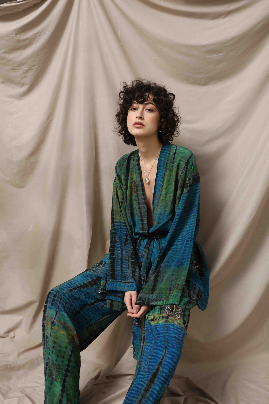 Model is wearing the Deep Teal Gorana Kimono Suit by House of Nomad Stories, featuring a relaxed silk kimono with matching belt and wide-leg trousers in a rich deep teal shade.