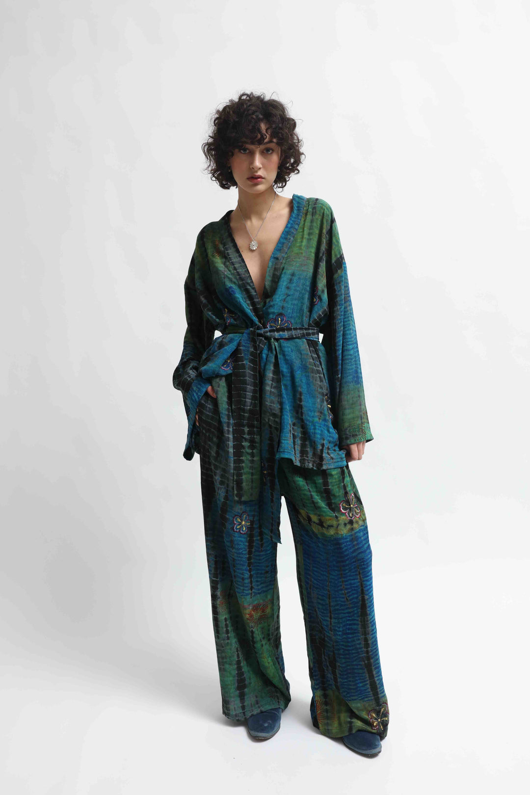 Model is wearing the Deep Teal Gorana Kimono Suit by House of Nomad Stories, featuring a relaxed silk kimono with matching belt and wide-leg trousers in a rich deep teal shade.