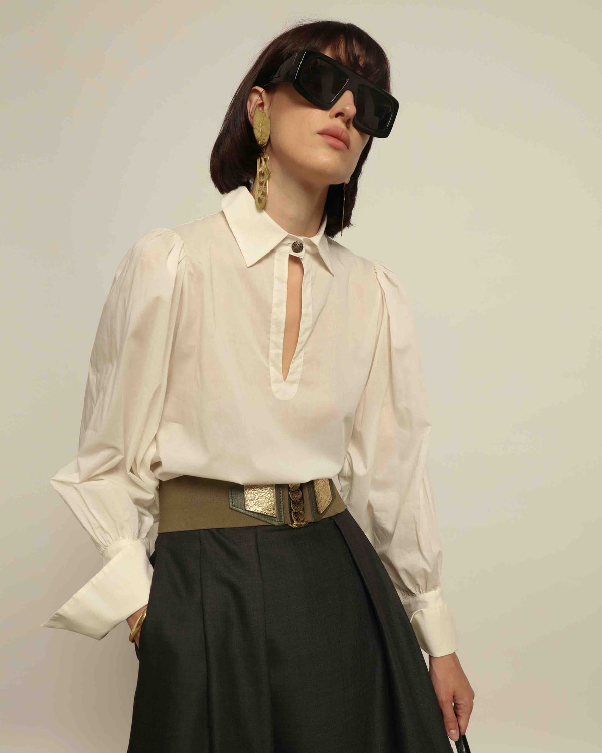 Model is wearing the Diana White Cotton Blouse by House of Nomad Stories, featuring a relaxed silhouette, soft V-neckline, dropped shoulders, wide cuffs, and a crisp white finish.
