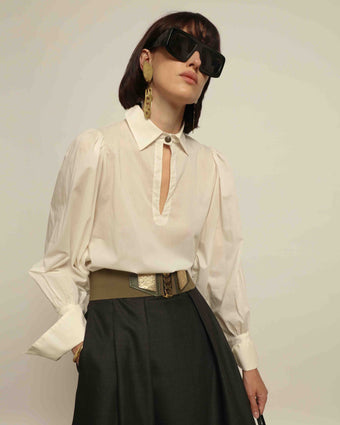 Model is wearing the Diana White Cotton Blouse by House of Nomad Stories, featuring a relaxed silhouette, soft V-neckline, dropped shoulders, wide cuffs, and a crisp white finish.
