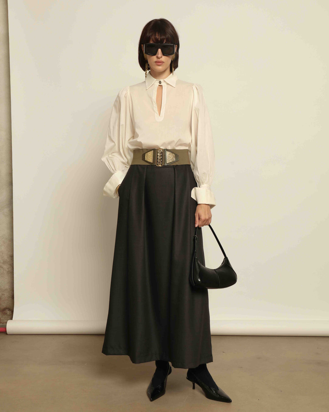 Model is wearing the Diana White Cotton Blouse by House of Nomad Stories, featuring a relaxed silhouette, soft V-neckline, dropped shoulders, wide cuffs, and a crisp white finish.
