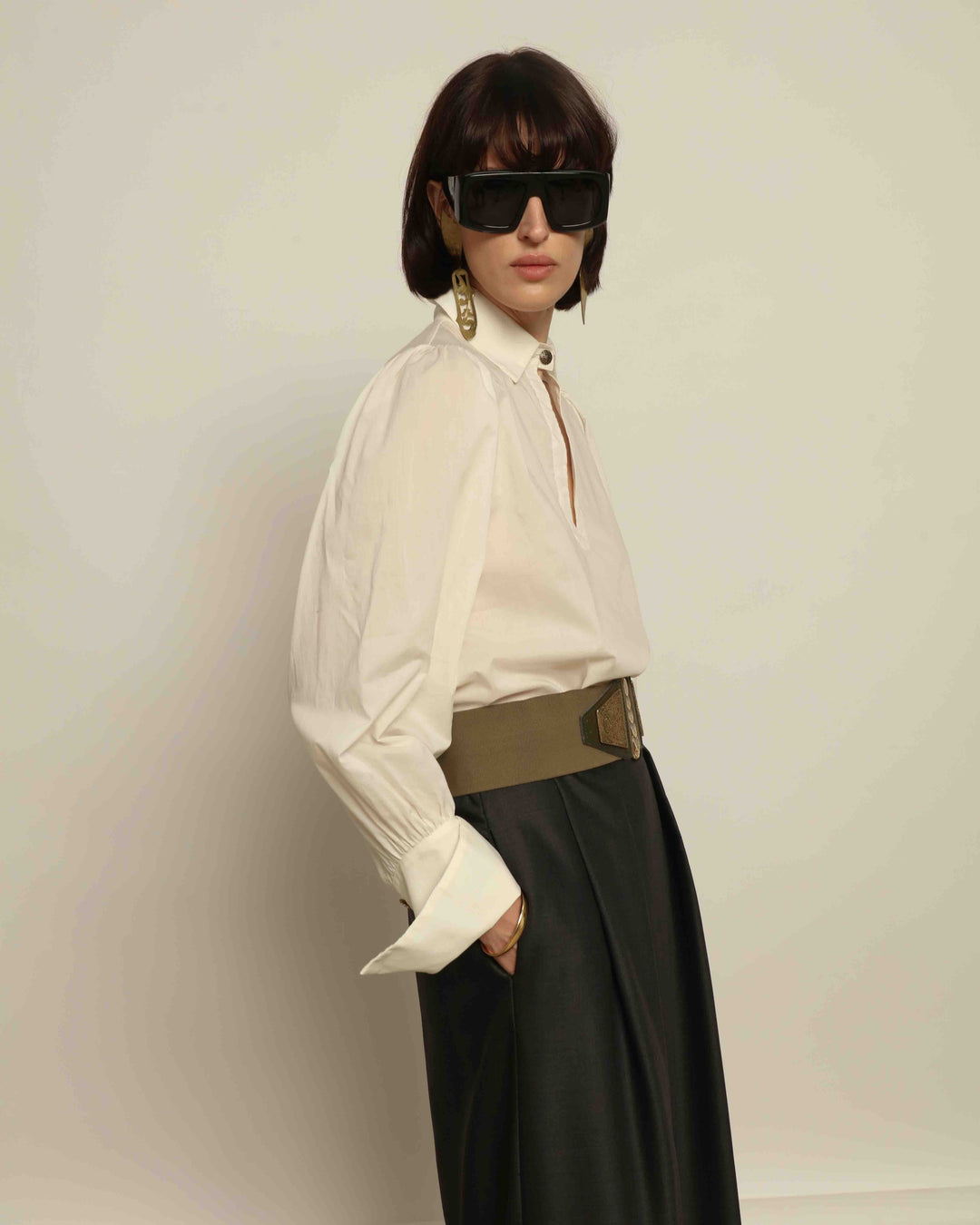 Model is wearing the Diana White Cotton Blouse by House of Nomad Stories, featuring a relaxed silhouette, soft V-neckline, dropped shoulders, wide cuffs, and a crisp white finish.
