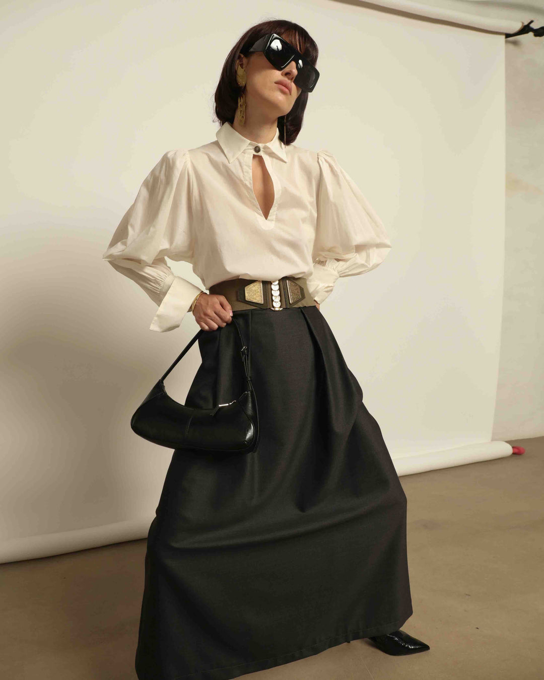 Model is wearing the Diana White Cotton Blouse by House of Nomad Stories, featuring a relaxed silhouette, soft V-neckline, dropped shoulders, wide cuffs, and a crisp white finish.
