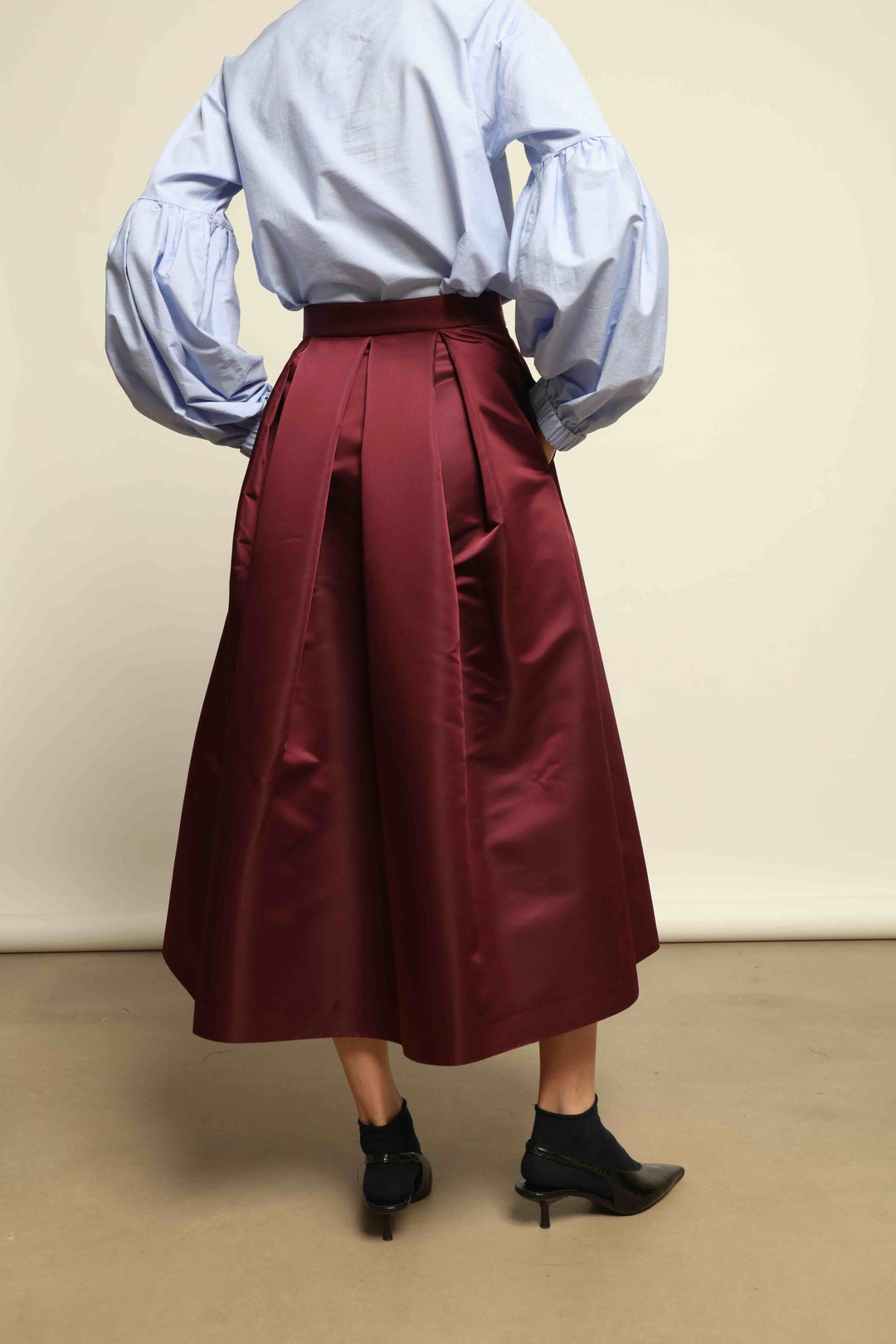 Model is wearing the Duchesse Violet Skirt by Lunatica Milano in mirtillo purple with box pleats and a flowing, elegant silhouette.