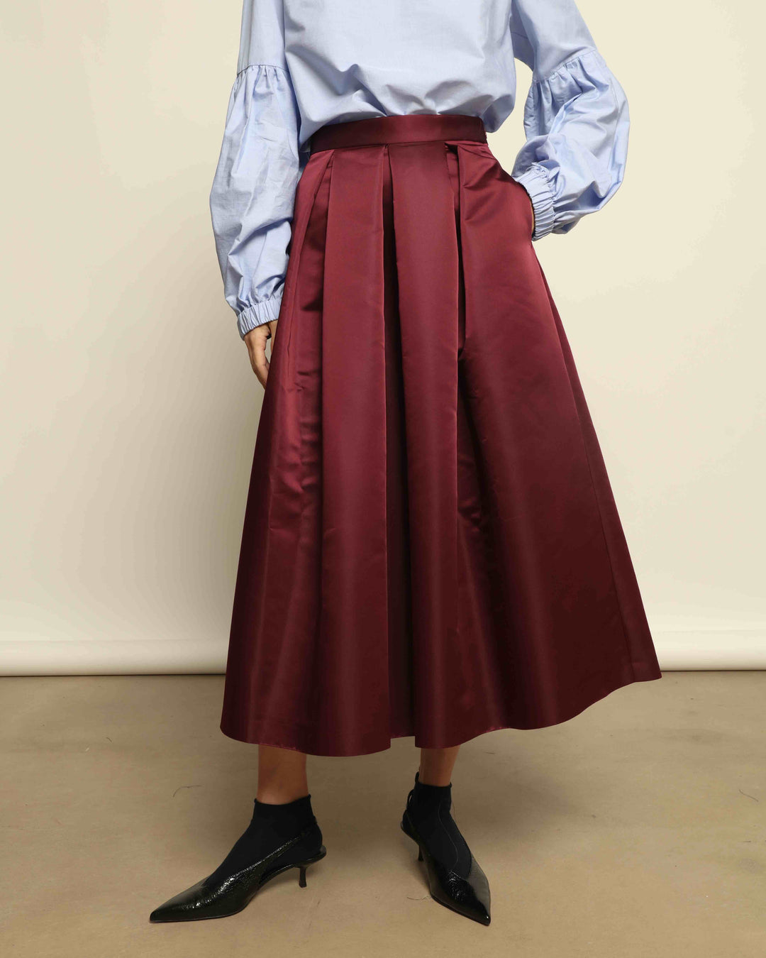 Model is wearing the Duchesse Violet Skirt by Lunatica Milano in mirtillo purple with box pleats and a flowing, elegant silhouette.