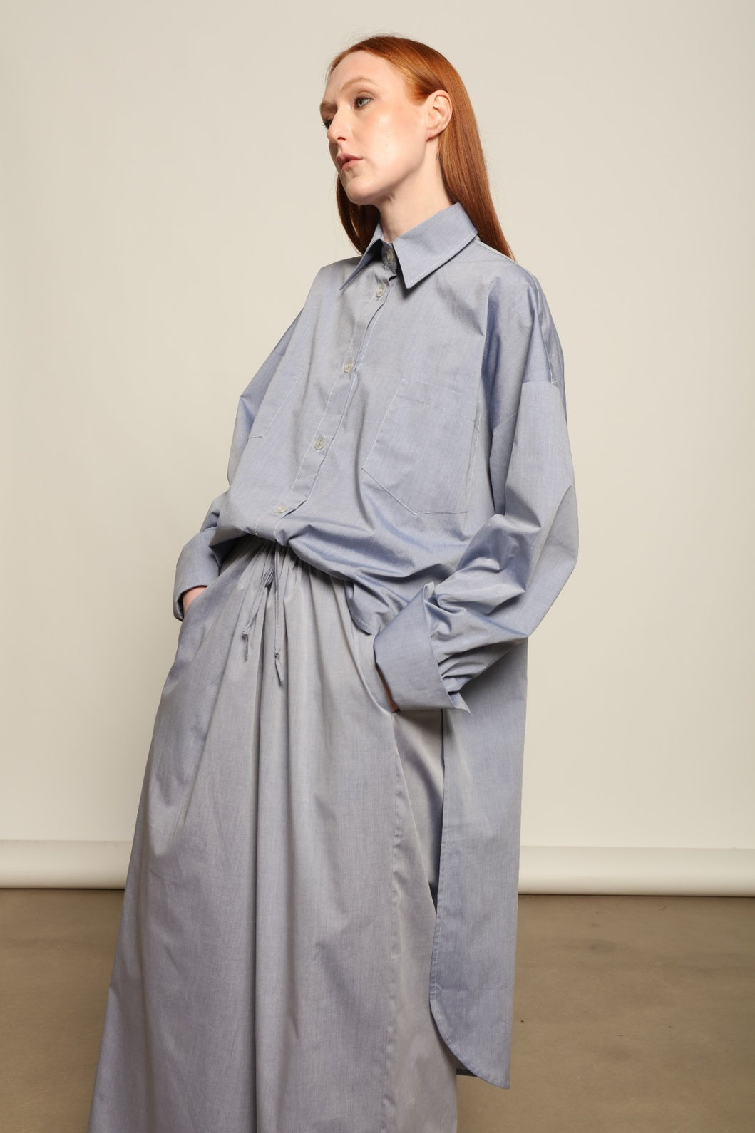 Model is wearing the Dusty Blue Bettina Long Shirt by House of Nomad Stories, crafted from 100% Ratti cotton with an elongated relaxed silhouette, soft dusty blue colour, and refined Italian craftsmanship.