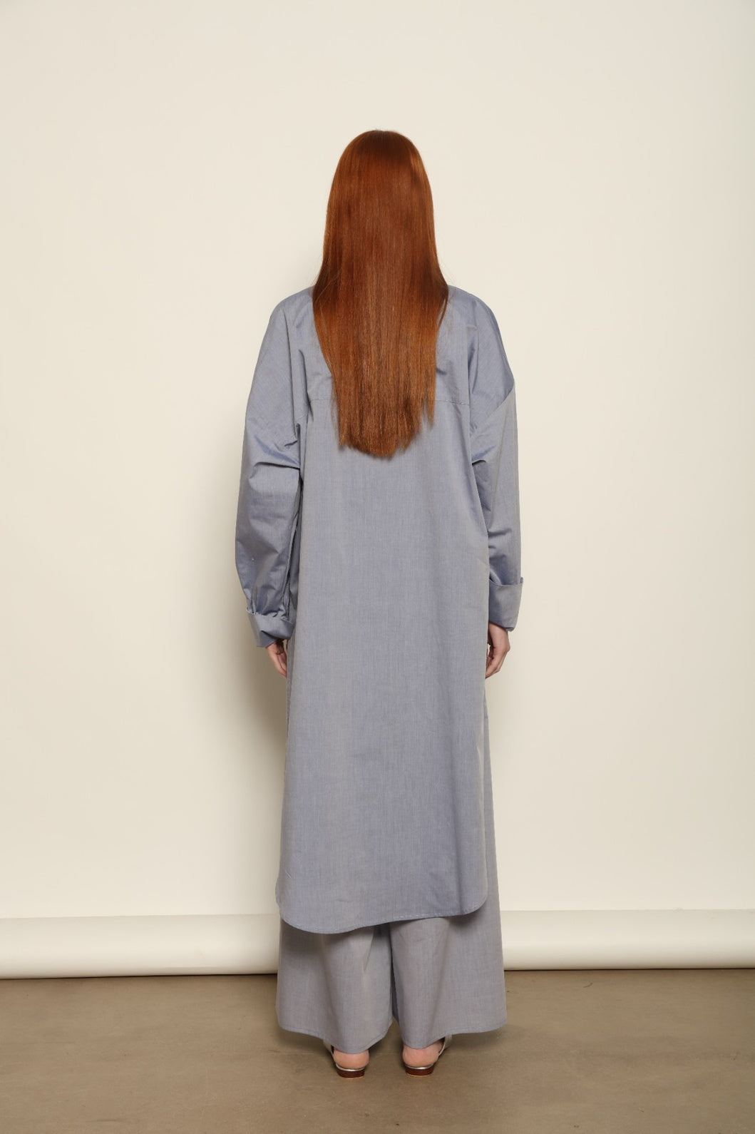 Model is wearing the Dusty Blue Bettina Long Shirt by House of Nomad Stories, crafted from 100% Ratti cotton with an elongated relaxed silhouette, soft dusty blue colour, and refined Italian craftsmanship.