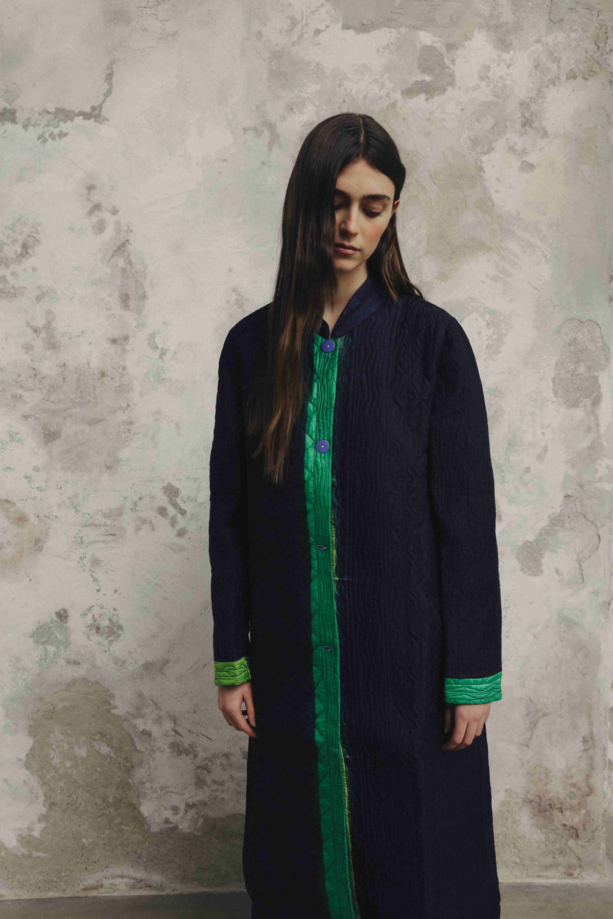 Model is wearing the Folklore 18 handmade silk coat by Injiri, featuring a navy blue exterior, green lining, 100% silk, and luxurious artisan craftsmanship.