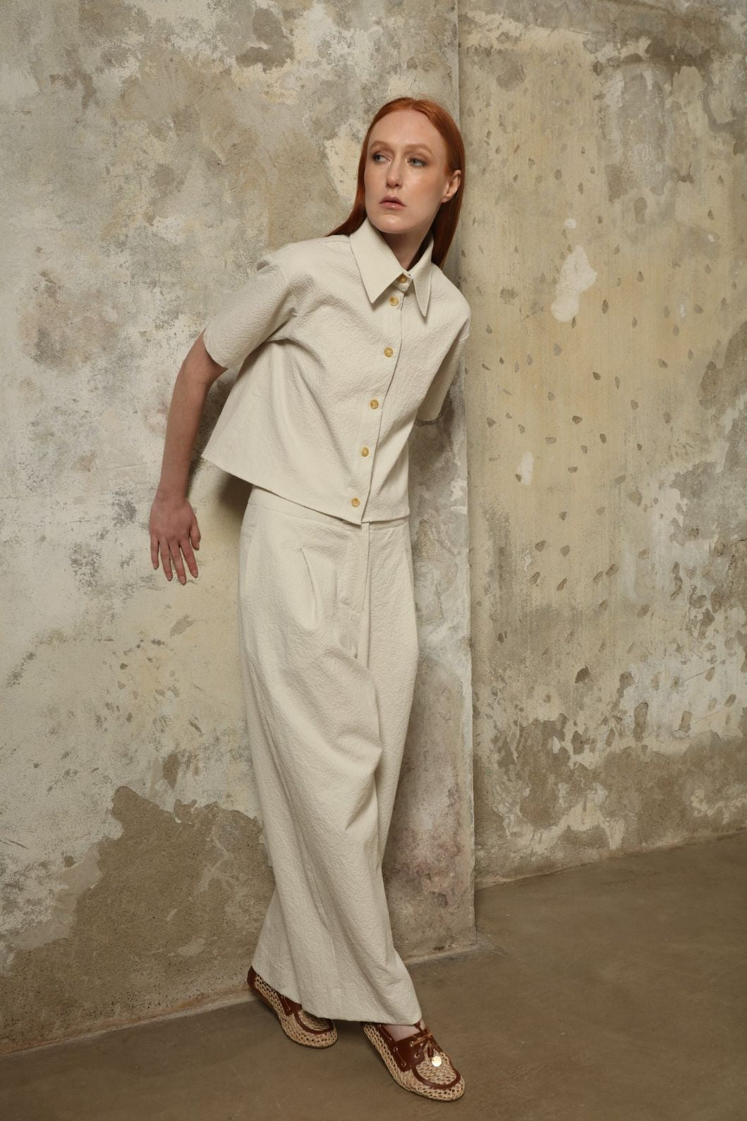 Model is wearing the Gabriella seersucker trousers from the House of Nomad Stories selection, lightweight and breathable women’s summer pants made in Italy, featuring a relaxed tailored silhouette designed for effortless movement and warm weather.