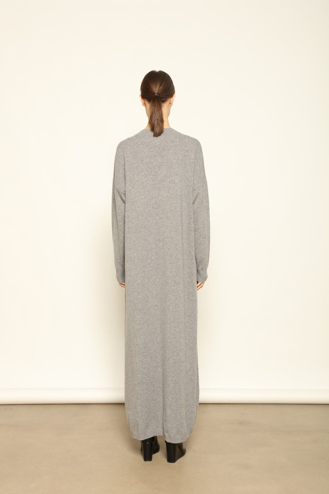Model is wearing the Graphite Katharina V-Neck Cashmere Maxi Dress by House of Nomad Stories, made from 100% pure Inner Mongolia cashmere, featuring a soft, breathable, warm knit with a long flowing silhouette, deep V-neckline, and timeless ethical luxury craftsmanship