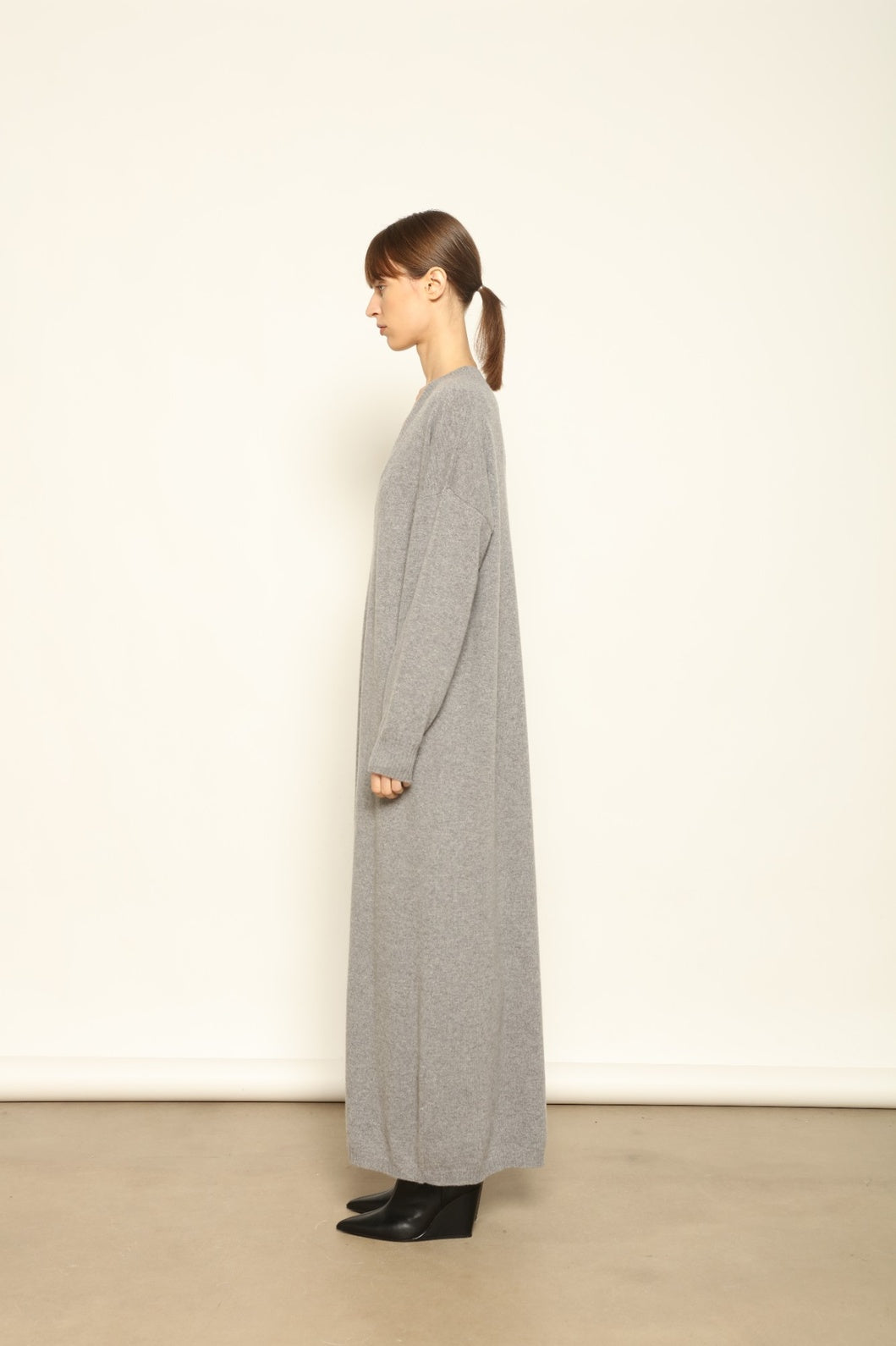 Model is wearing the Graphite Katharina V-Neck Cashmere Maxi Dress by House of Nomad Stories, made from 100% pure Inner Mongolia cashmere, featuring a soft, breathable, warm knit with a long flowing silhouette, deep V-neckline, and timeless ethical luxury craftsmanship