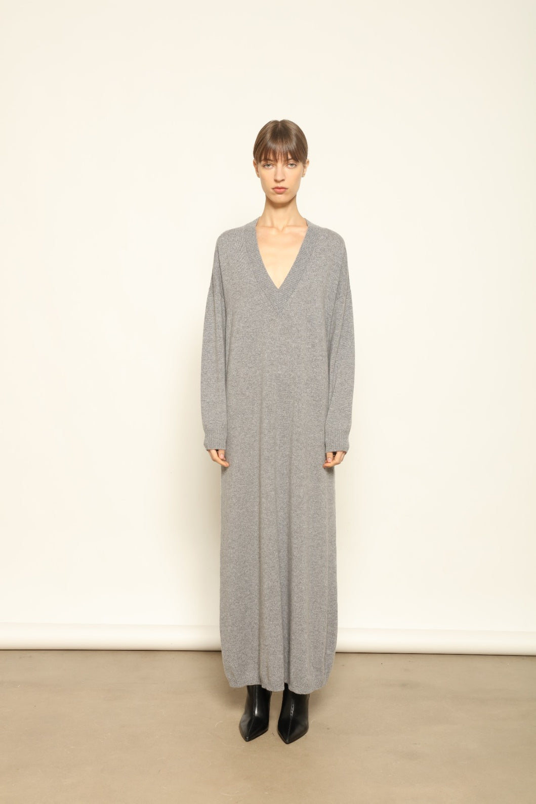 Model is wearing the Graphite Katharina V-Neck Cashmere Maxi Dress by House of Nomad Stories, made from 100% pure Inner Mongolia cashmere, featuring a soft, breathable, warm knit with a long flowing silhouette, deep V-neckline, and timeless ethical luxury craftsmanship