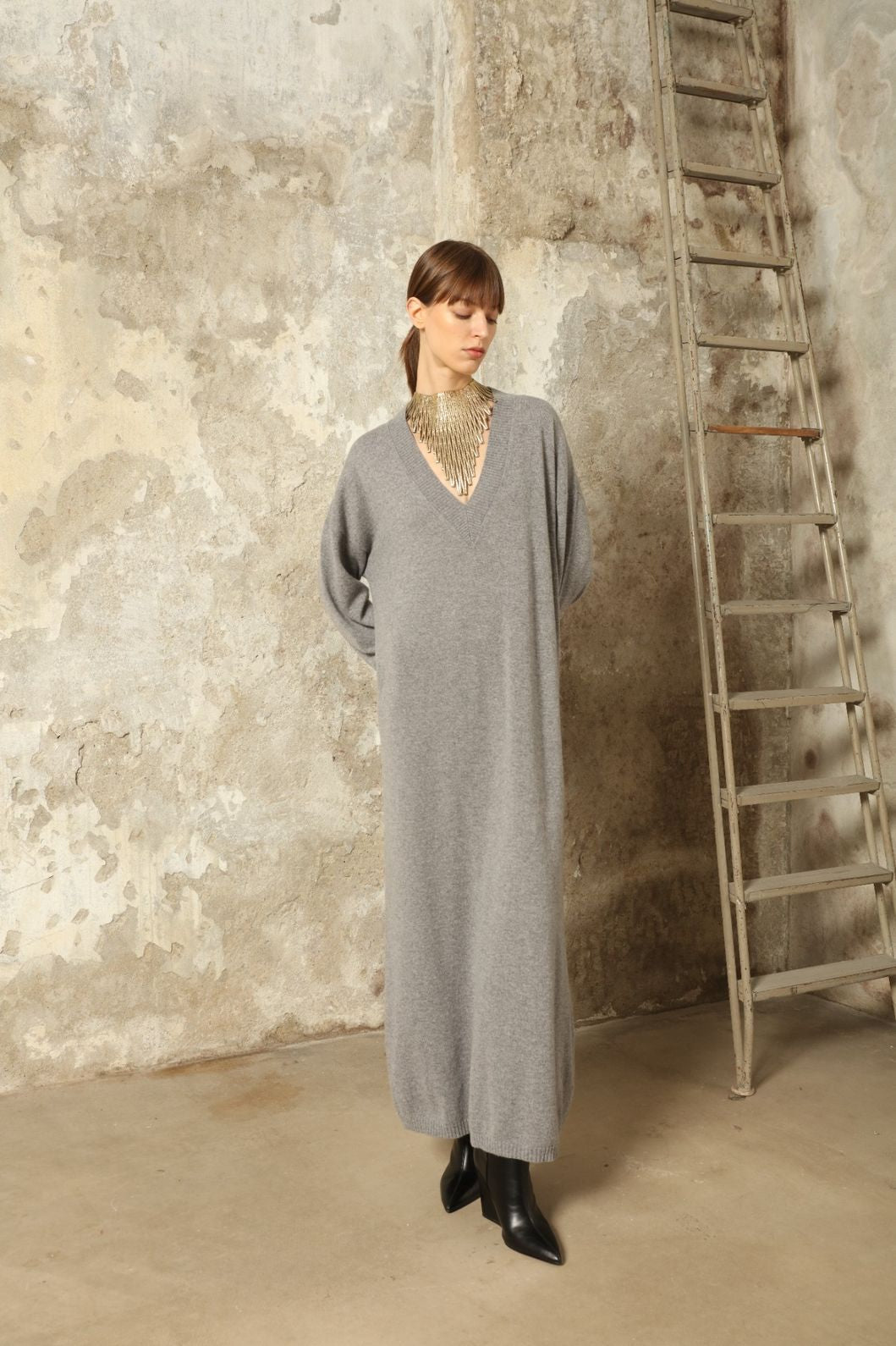 Model is wearing the Graphite Katharina V-Neck Cashmere Maxi Dress by House of Nomad Stories, made from 100% pure Inner Mongolia cashmere, featuring a soft, breathable, warm knit with a long flowing silhouette, deep V-neckline, and timeless ethical luxury craftsmanship