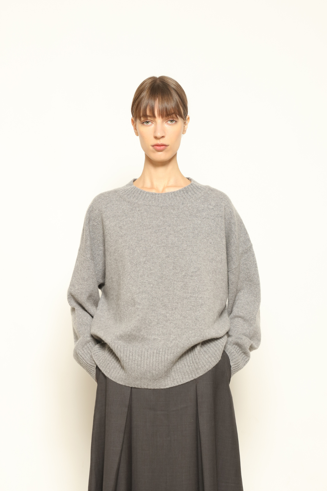 Model is wearing the graphite Noemi Round Neck Pullover by House of Nomad Stories, crafted from 100% pure Inner Mongolia cashmere, featuring ultra-soft, breathable, durable knitwear, relaxed fit, round neckline, and timeless ethical luxury design